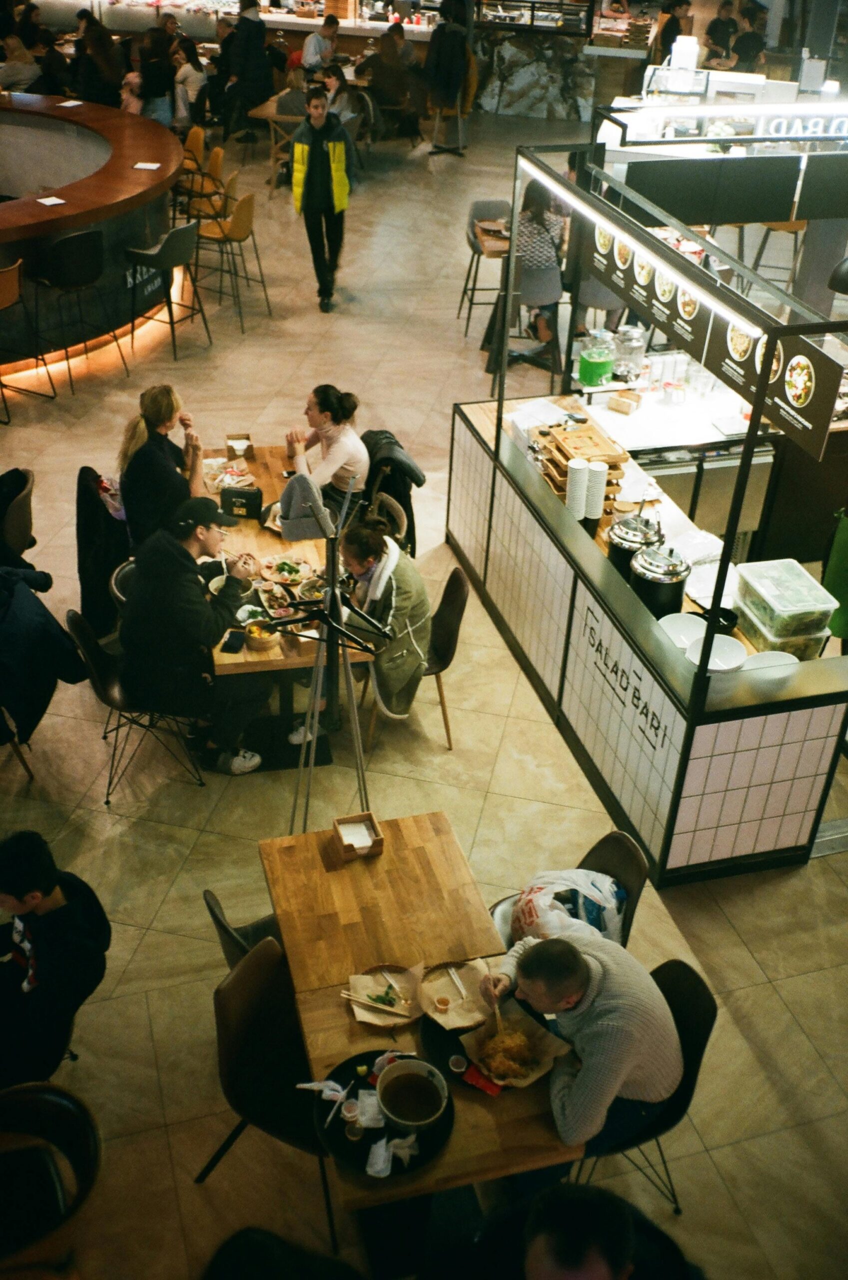 Overhead shot of people dining at an indoor food court with diverse food stalls.